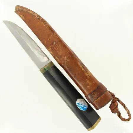 Puukko, Design Tapio Wirkkala, ruostumatonta terästä, nailonia ja messinkiä, terässä käytön jälkiä ja lohkeamia, nahkatuppi Lähetetään postipakettina.