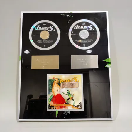 Jean S. Sammakkoprinssi Kulta- ja platinalevylevy vuodelta 2003 ja 2004, Jussi S. Kivimäki, mitat 40,5x33,5cm. Ota yhteys panttilainaamoon kuljetusmaksusta sopimiseksi.