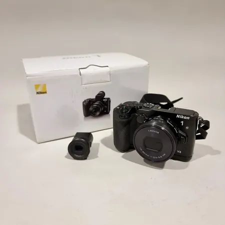 Järjestelmäkamera, Nikon 1 V3 runko, näytössä vaalea kuvaa ympäröivä kehä (ei vaikutusta otettuihin kuviin), Nikkor 10-30/3.5-5.6 VR PD-ZOOM objektiivi, Nikon EVF(1 V3) etsin ja Nikon GR-N1010 Grip,  mukana laturi, manuaali ja laatikko