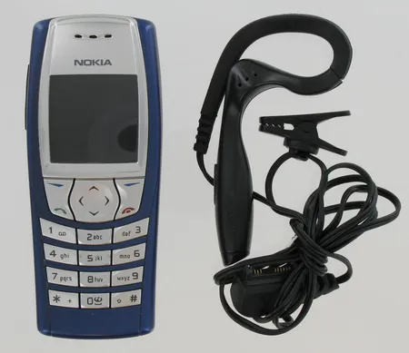 Matkapuhelin Nokia 6610i, laturi, nappikuuloke, ylimääräinen akku ja näppäinmatto.
